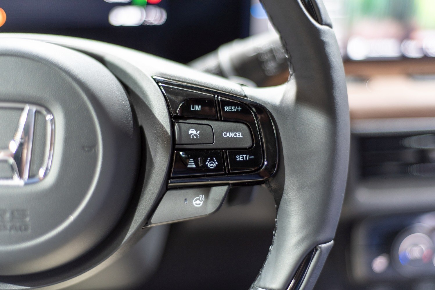 Close-up of steering wheel control buttons and leather wrap