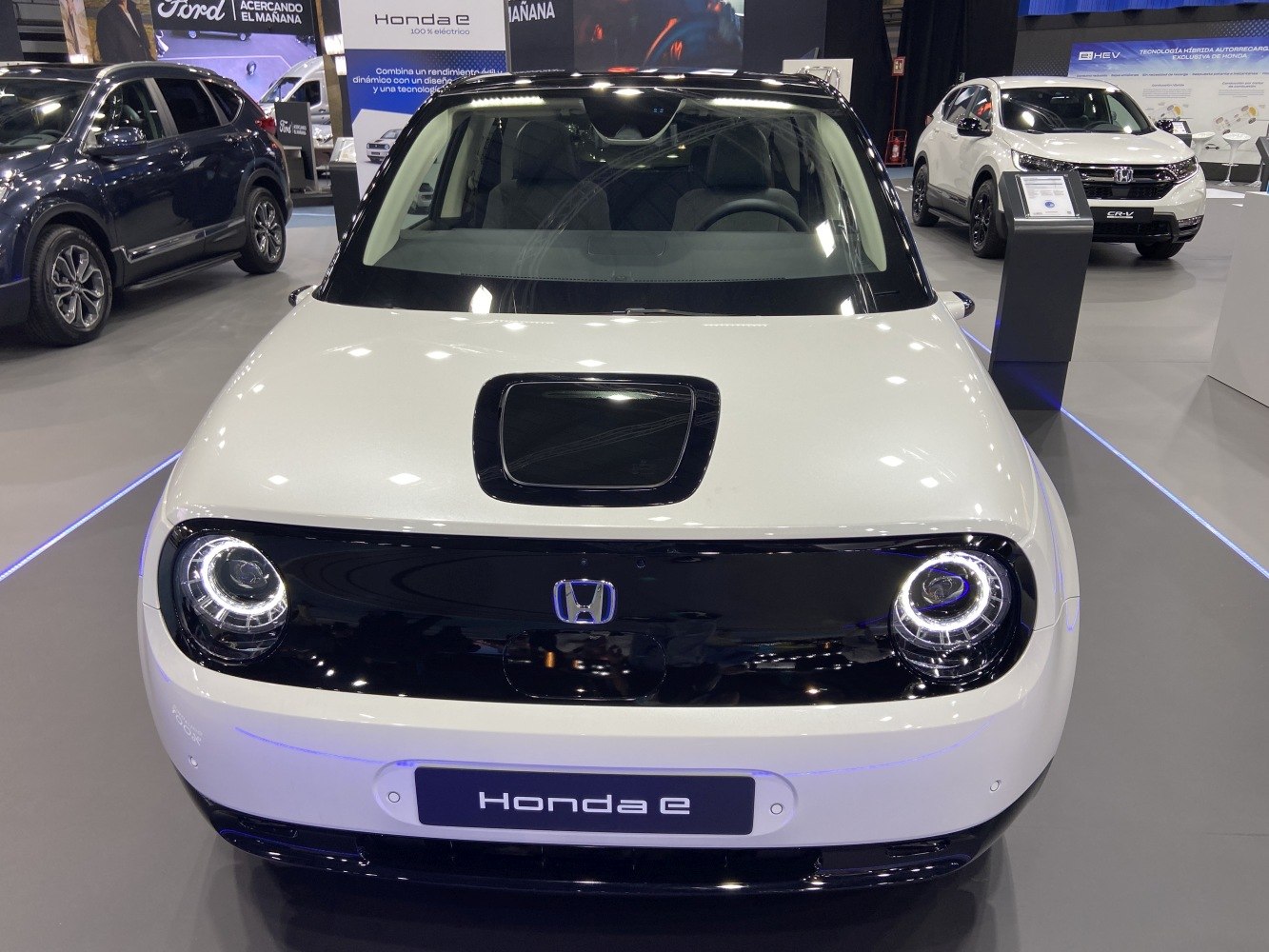 Front view of a compact electric vehicle with round LED headlights and black-white color scheme