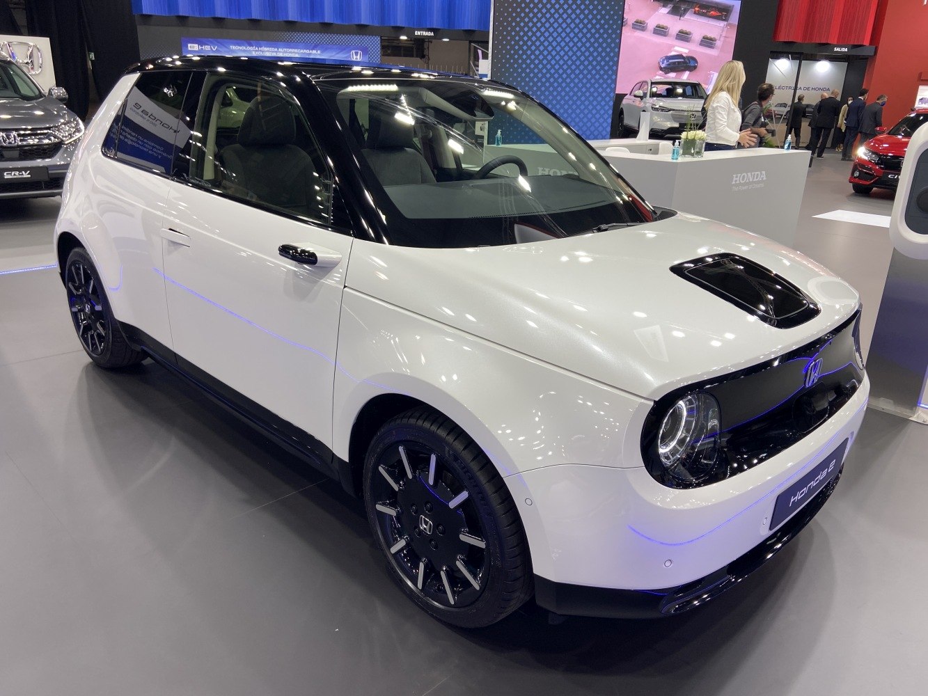 Front three-quarter view of a compact electric hatchback with two-tone black and white paint and LED circular headlights.