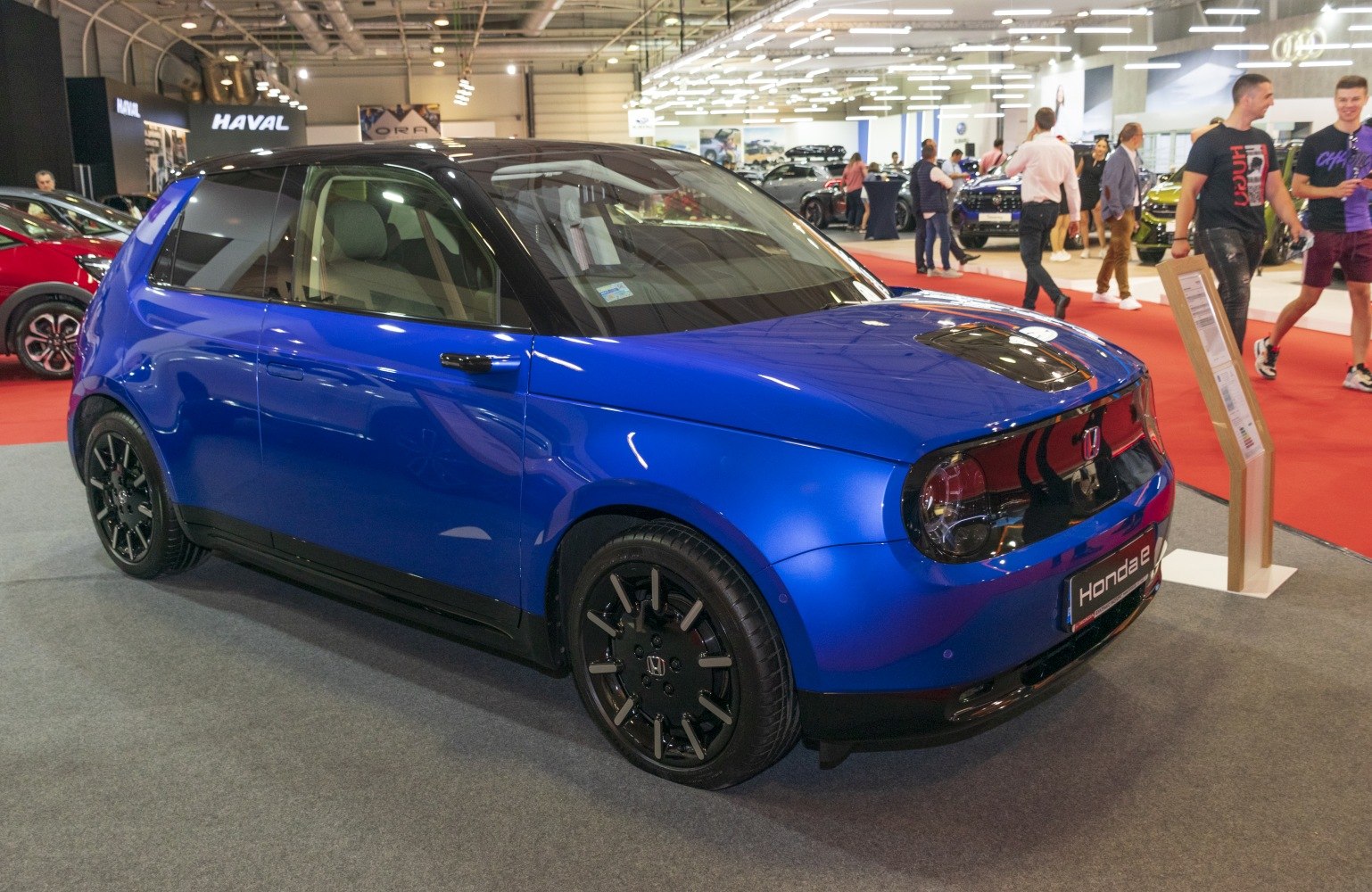 Blue compact electric vehicle with black roof and modern design front side view