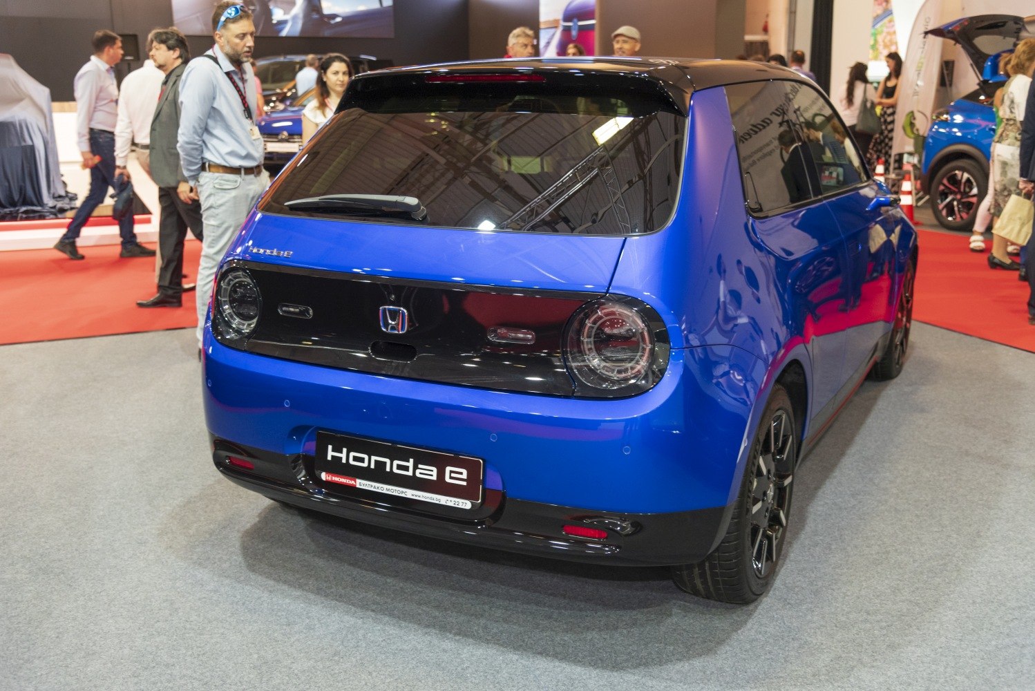 Rear view of blue electric hatchback with round tail lights and black rear panel