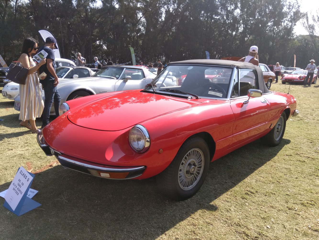 Red convertible sports car with round headlights and black soft top.