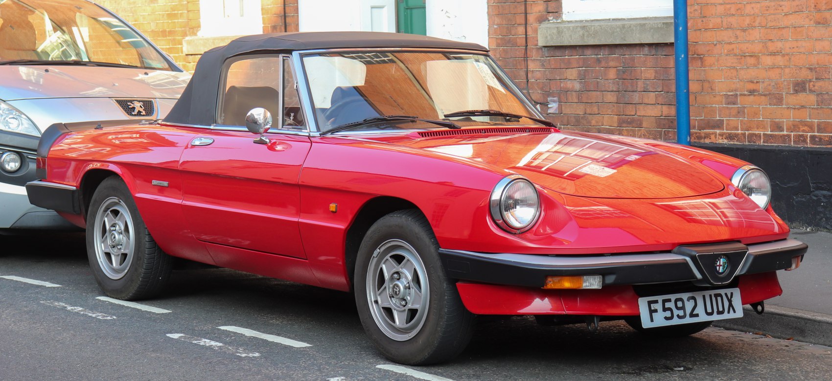 Red convertible with black soft top, round headlights, classic wheels.