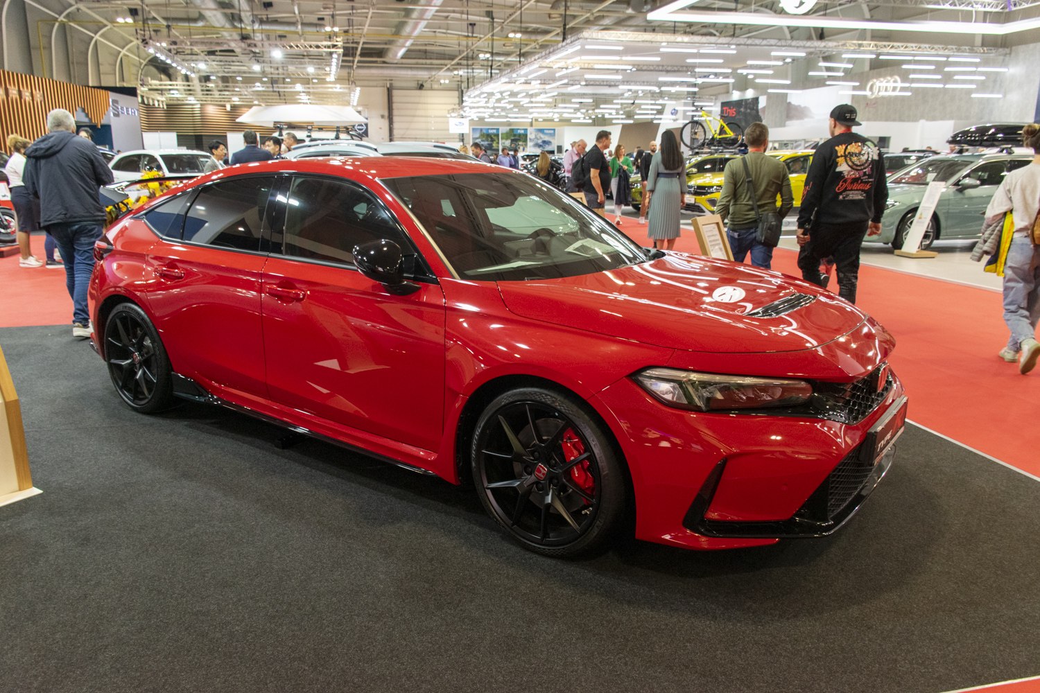 Red sporty hatchback with black alloy wheels and aerodynamic body