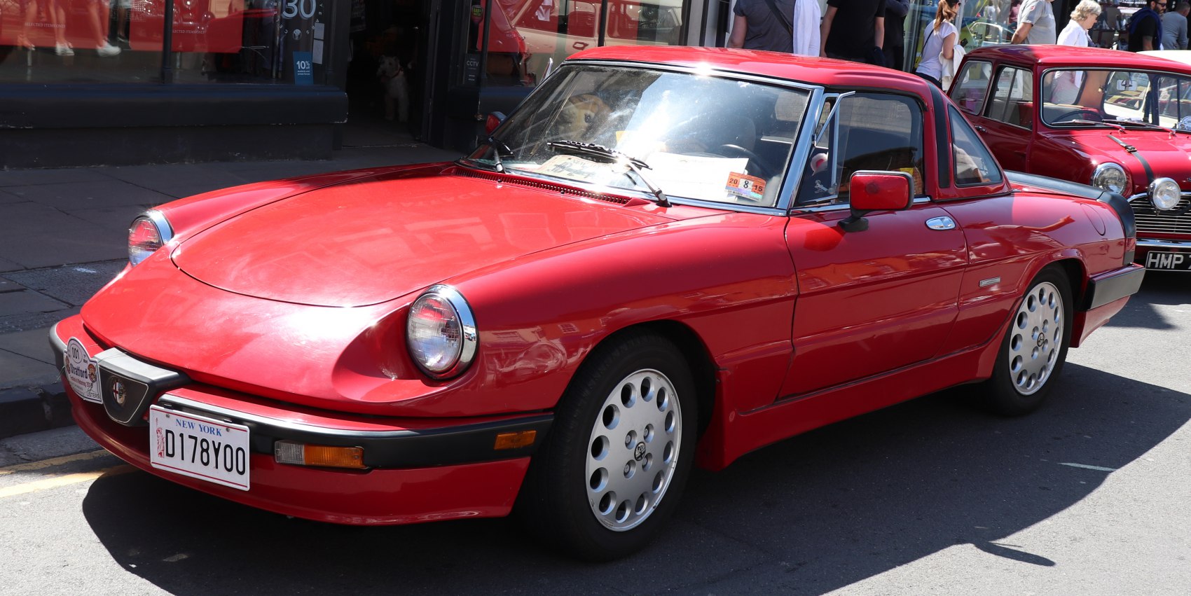 Red vintage sports car with round headlights and alloy wheels.