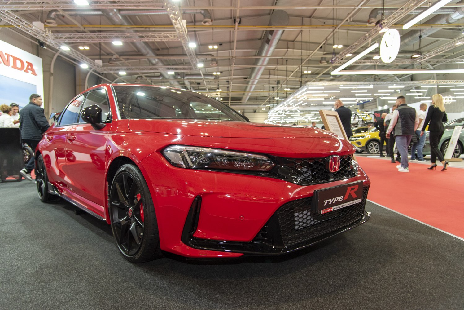 Sporty red hatchback with black grille, headlights, and wheels.