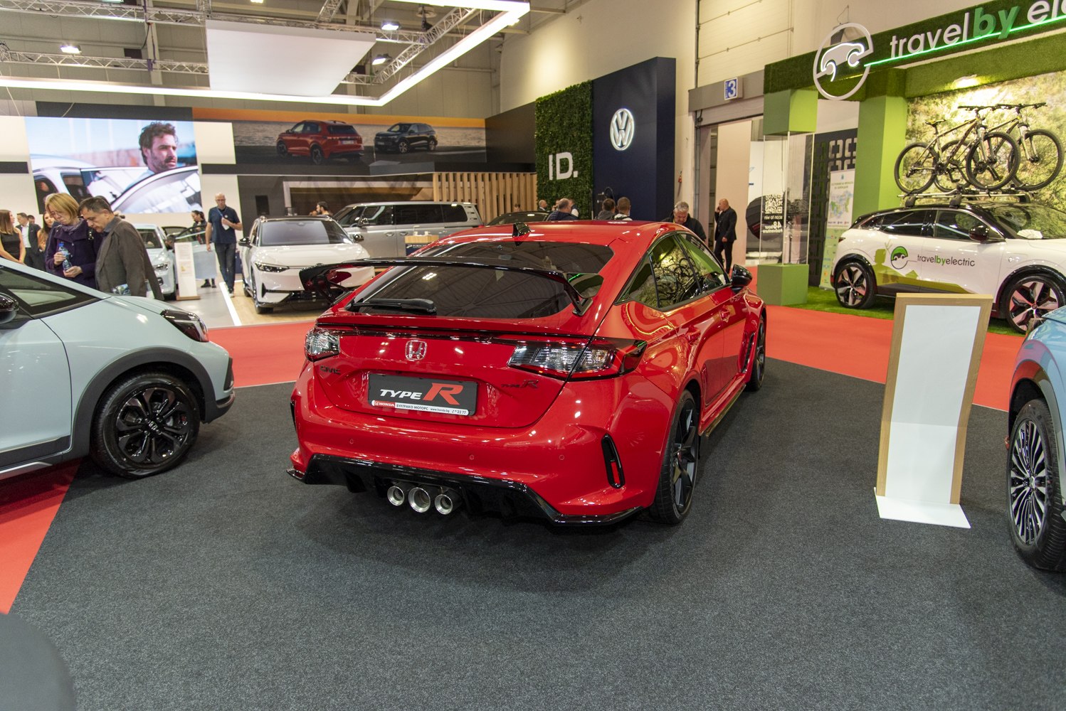 Rear view of red hatchback with triple exhaust and large rear spoiler.