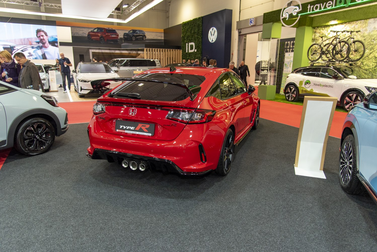 Red hatchback with rear spoiler and triple exhaust pipes