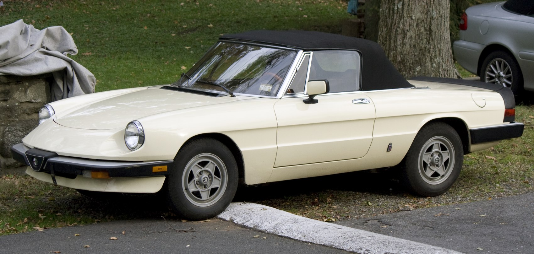 Convertible sports car with pop-up headlights and black soft top