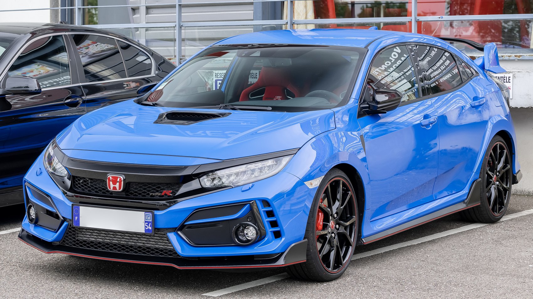 Blue aggressive front with hood scoop and large rear wing spoiler.