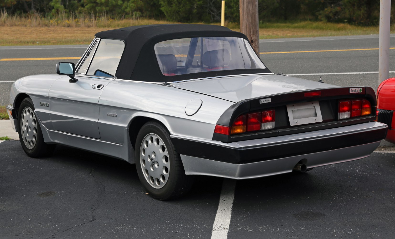 Rear side view of classic convertible with black soft top and distinctive taillights.