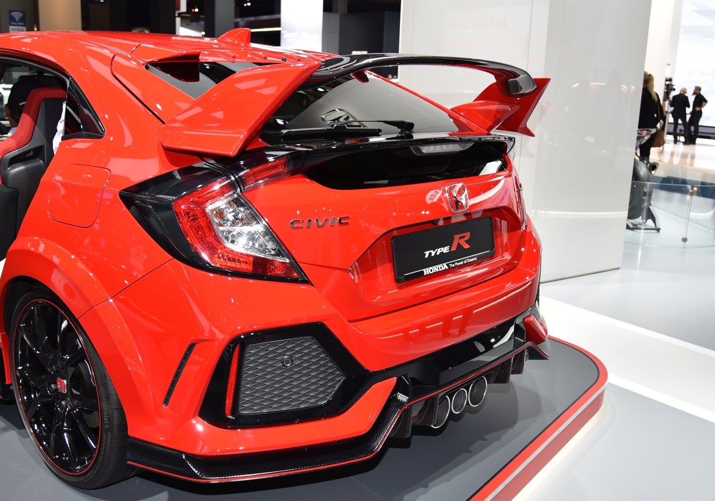 Rear view with triple exhaust, large wing spoiler, and sporty design elements.