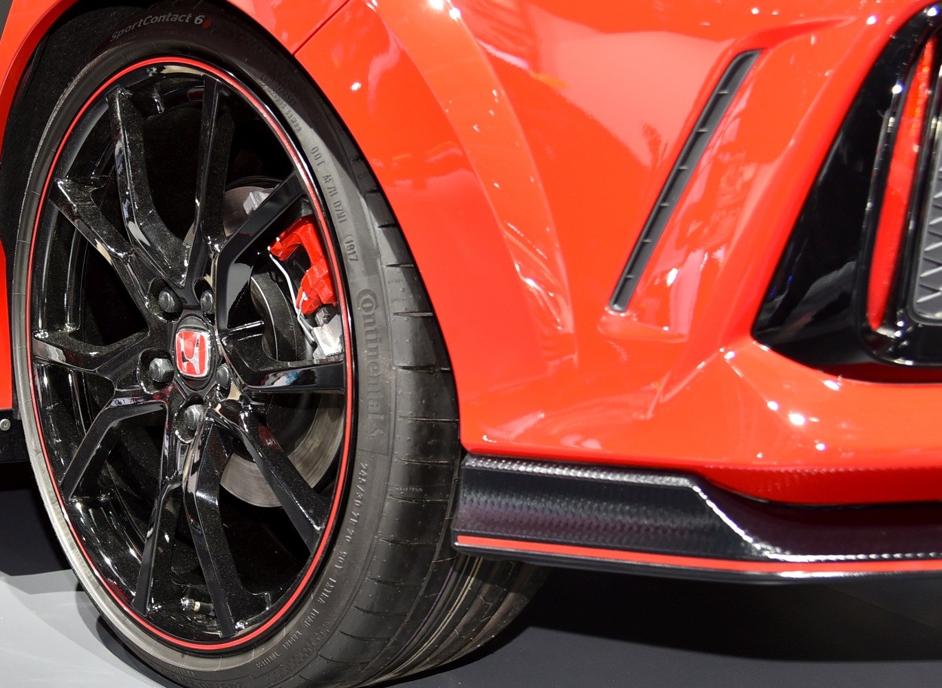 Glossy black alloy wheel with red brake caliper and sport tire