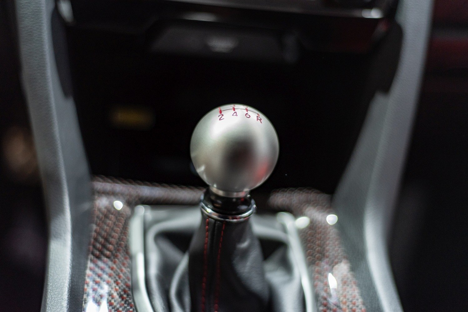 Close-up of metal manual gear shift knob with 6-speed pattern.