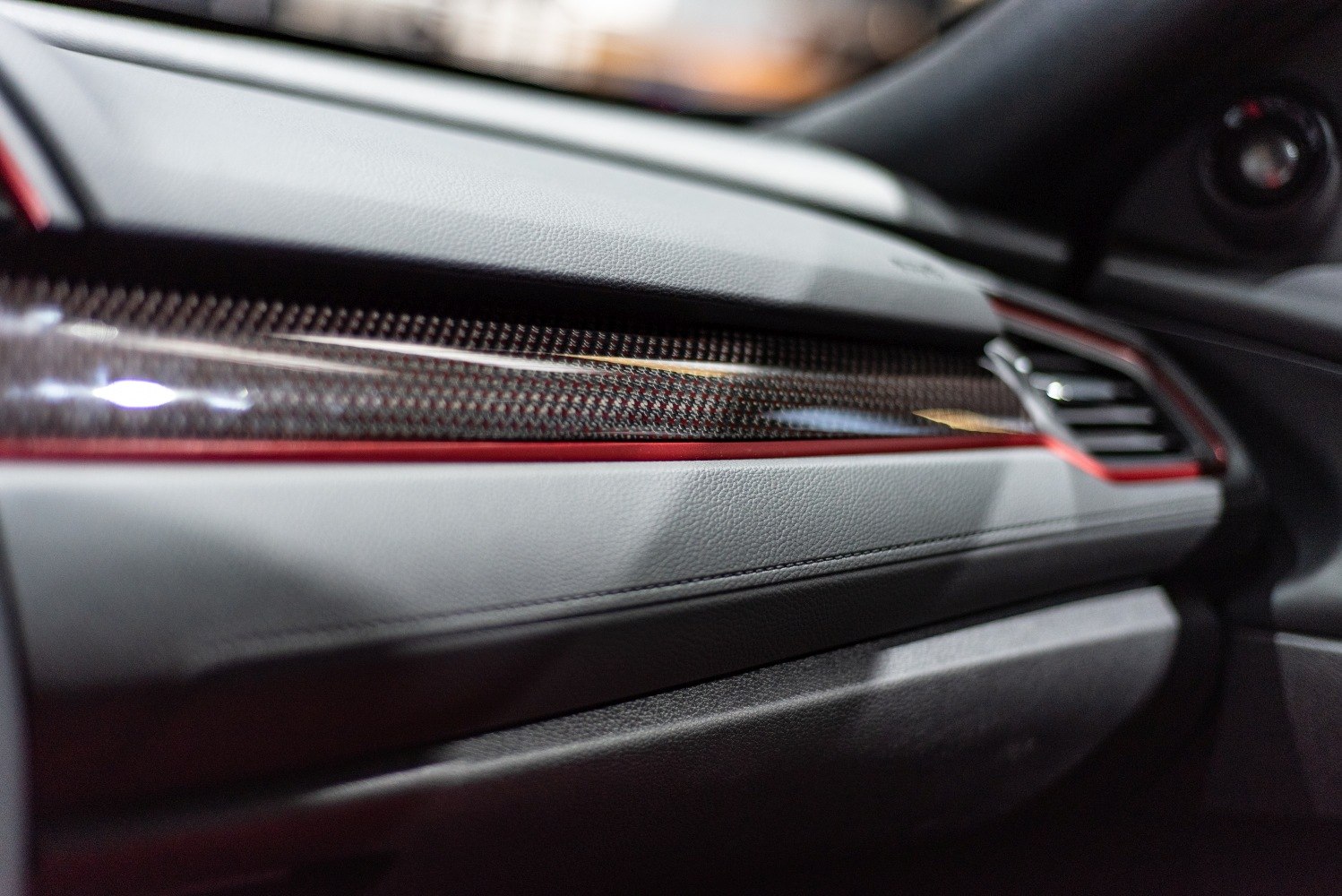 Close-up of sporty carbon fiber and red-accented dashboard trim