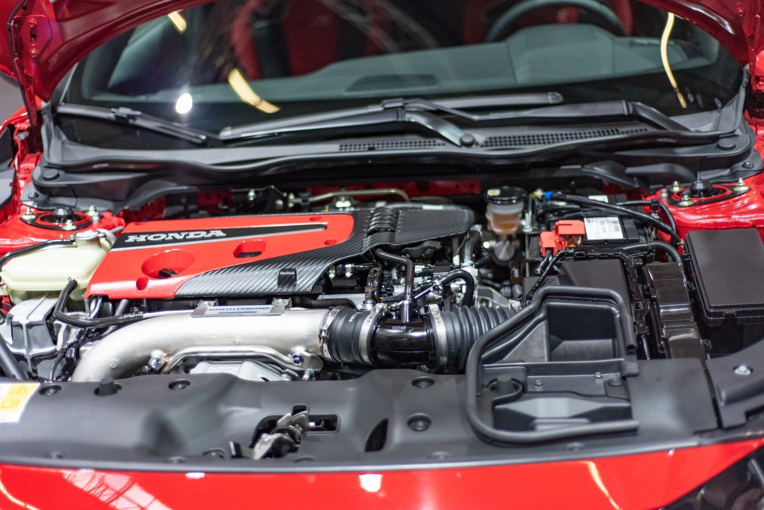 Close-up of red turbocharged engine cover and components in an engine bay