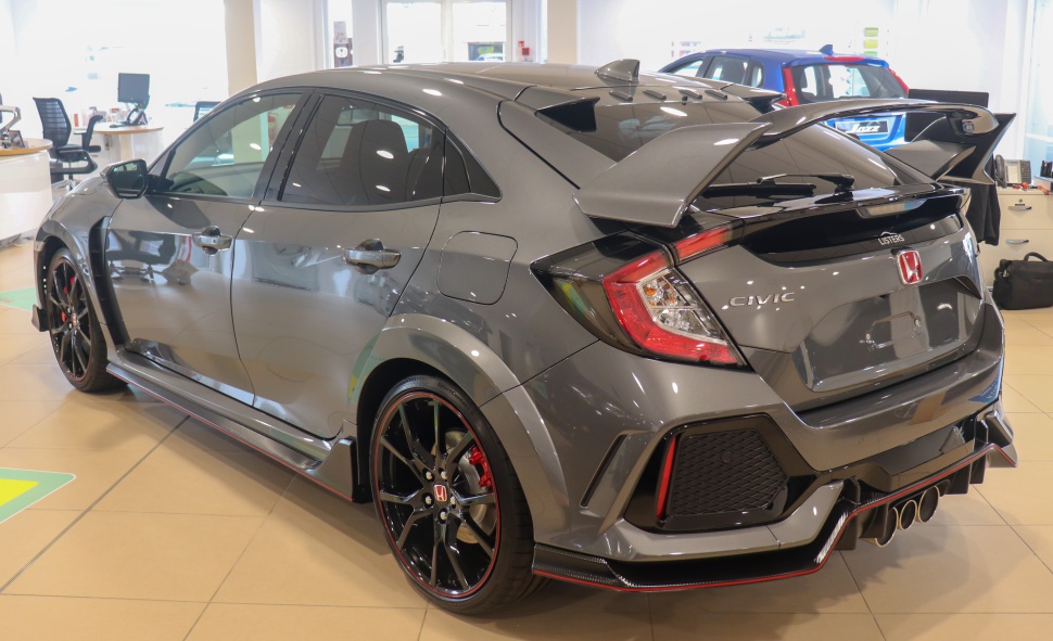 Sporty hatchback rear side with large spoiler and triple central exhausts