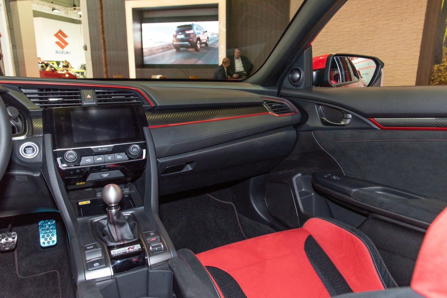 Sporty manual gear shift and red-accented dashboard with racing seats interior