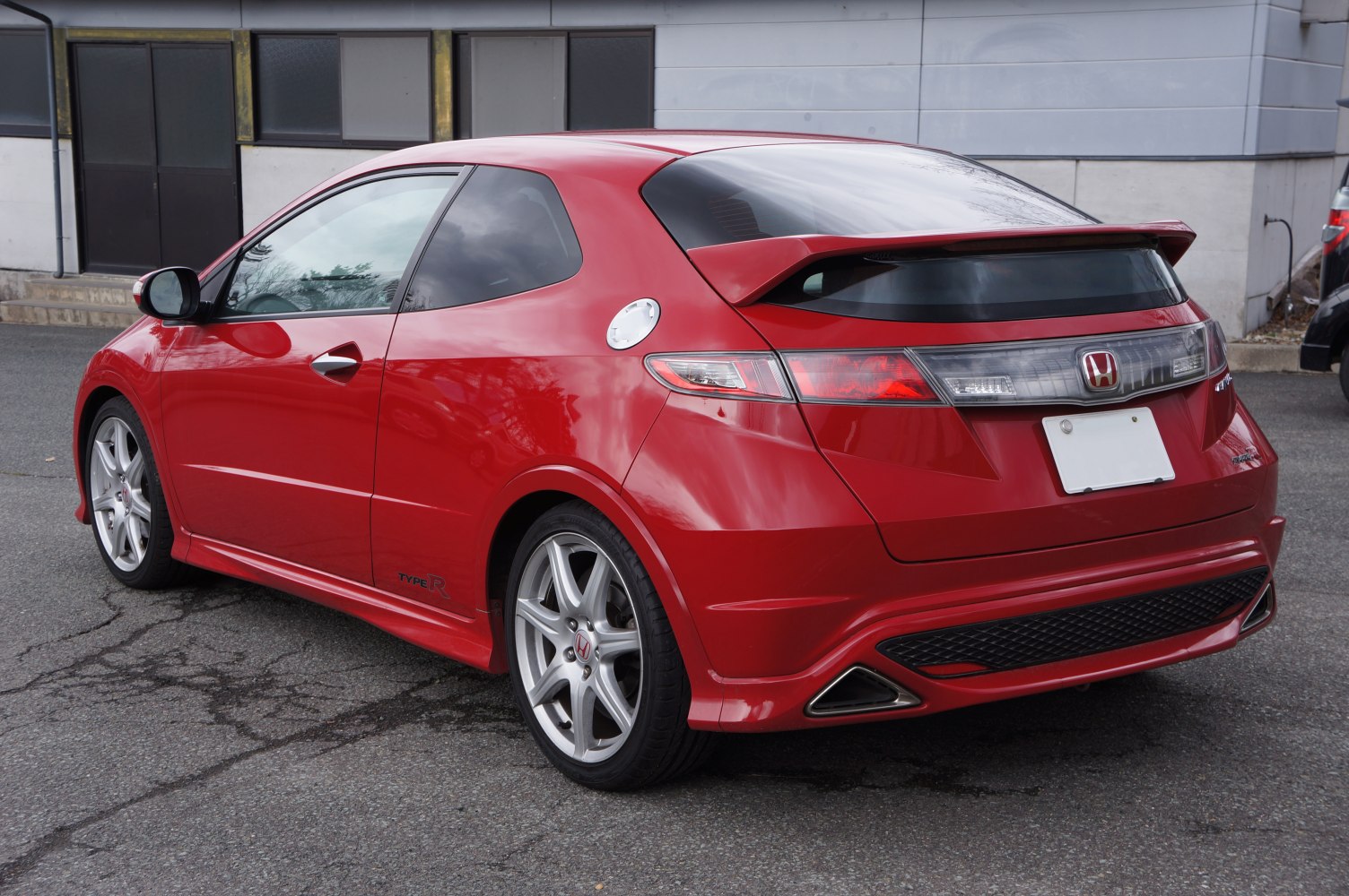Red sporty hatchback with rear wing and alloy wheels