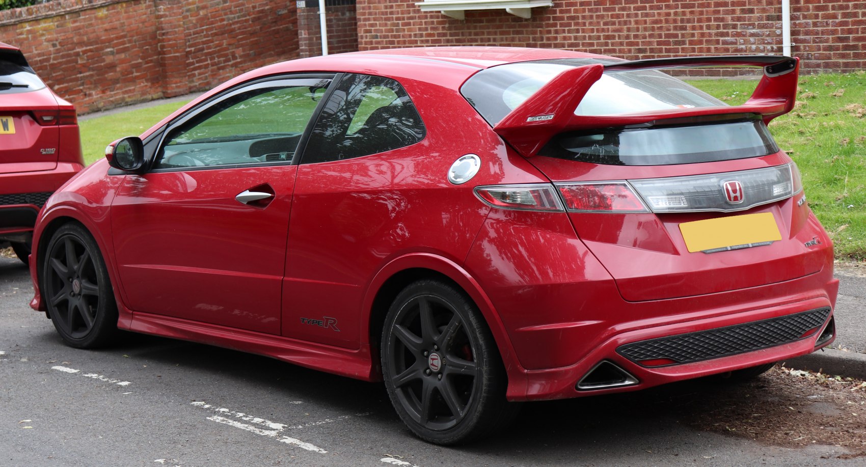 Sporty hatchback rear side with large wing and black rims
