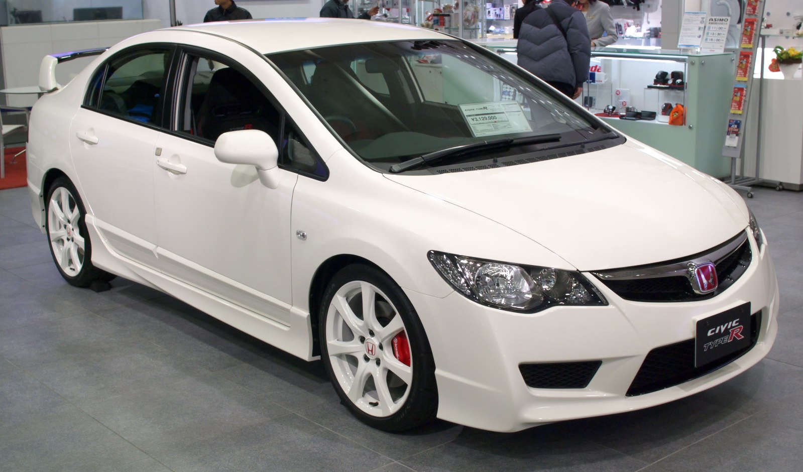 White sporty sedan with rear spoiler and alloy wheels
