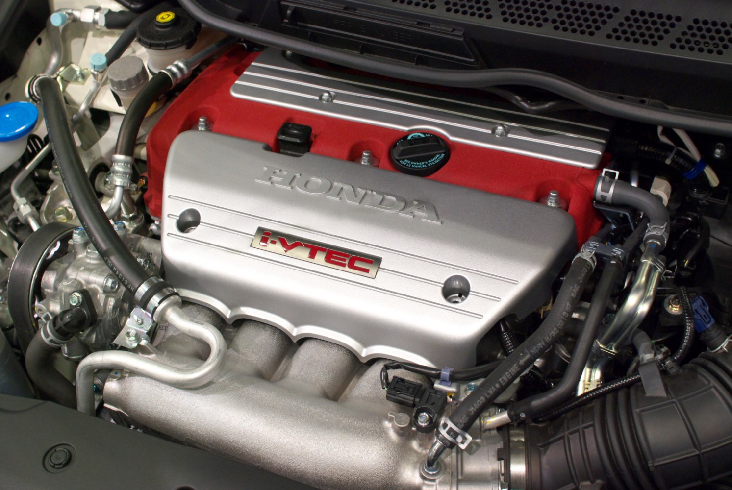 Close-up of a high-performance i-VTEC engine with red valve cover and intake manifold
