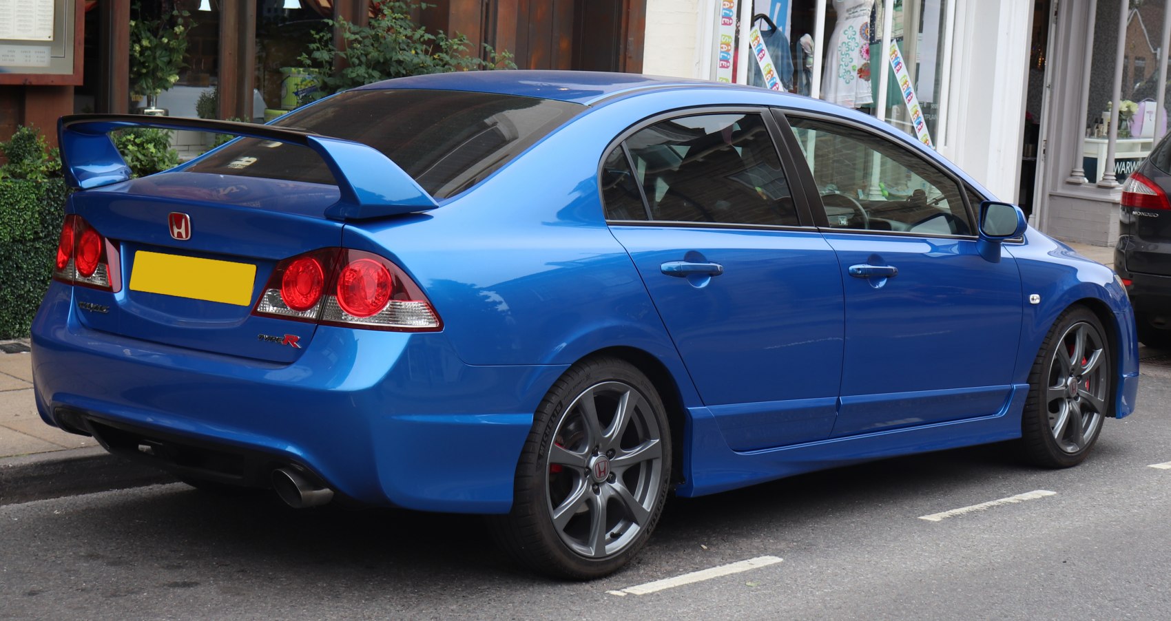 Rear spoiler and sporty alloy wheels on blue performance sedan