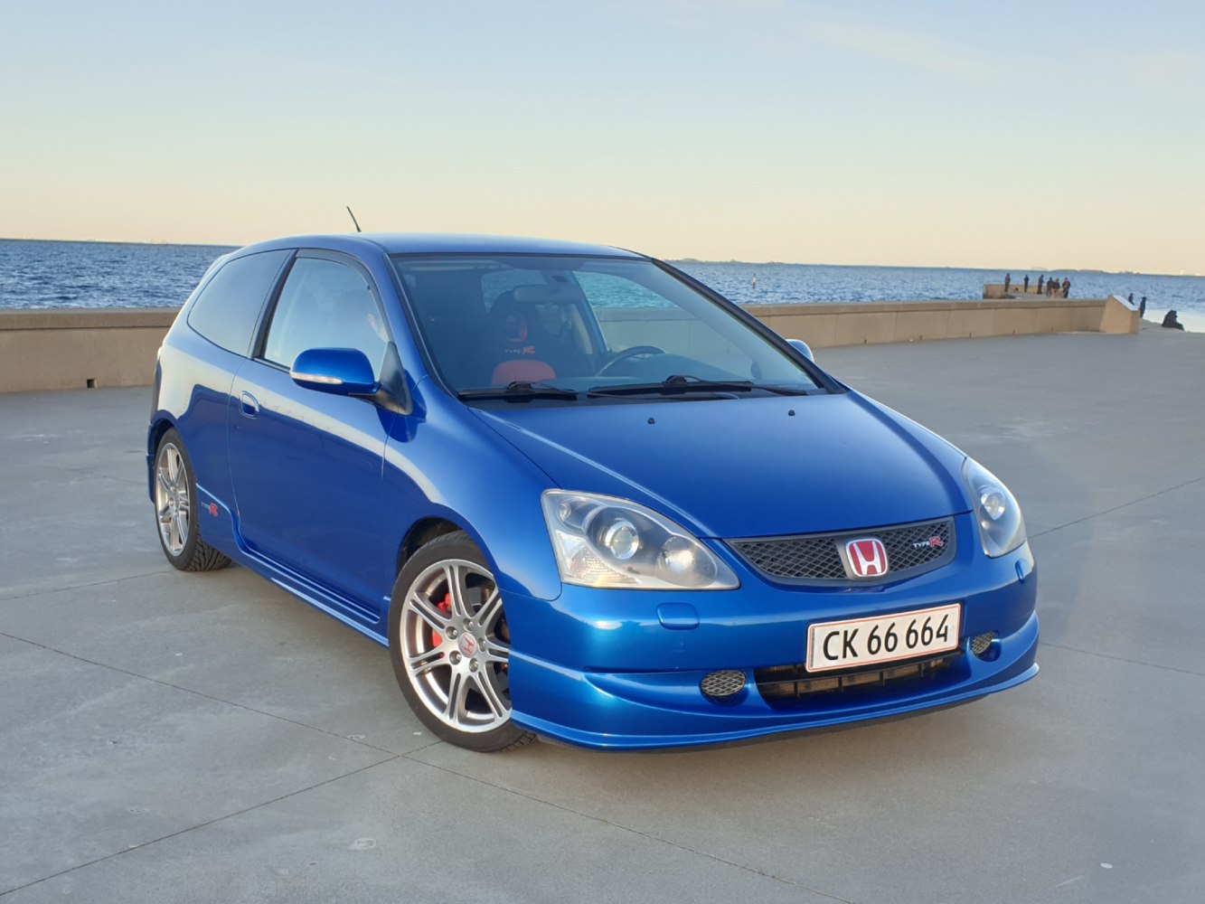 Blue hatchback with sporty wheels and red brake calipers front-side view