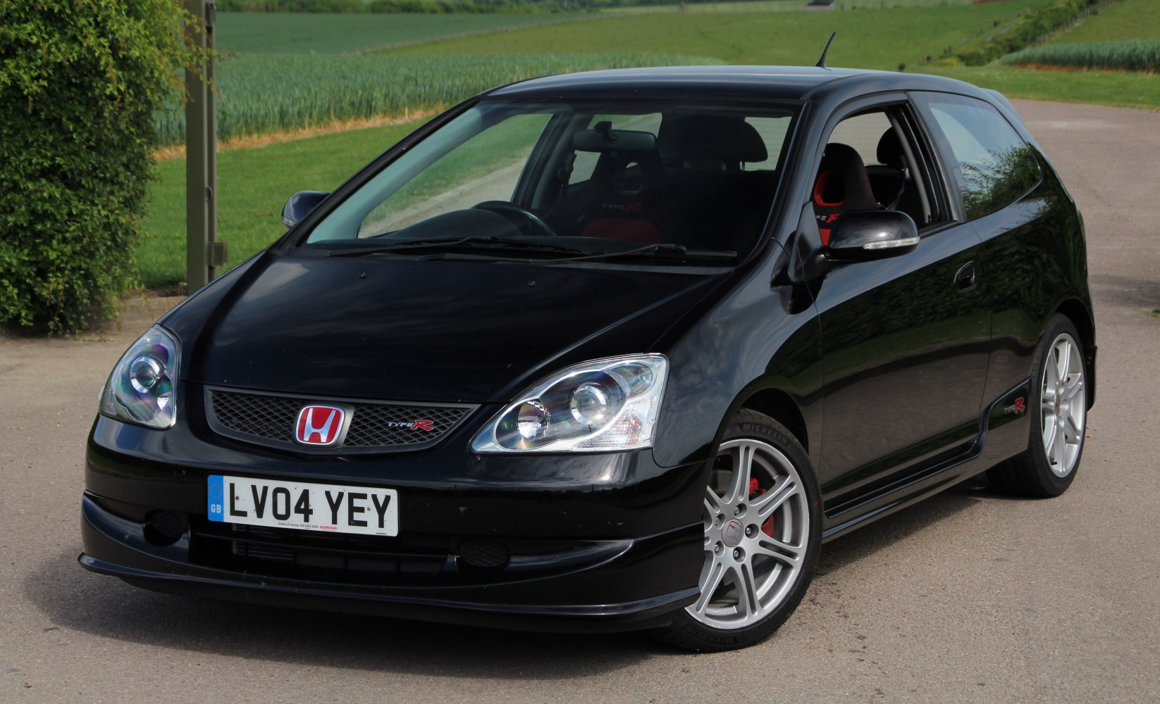Front and side view of a black sporty hatchback with alloy wheels.