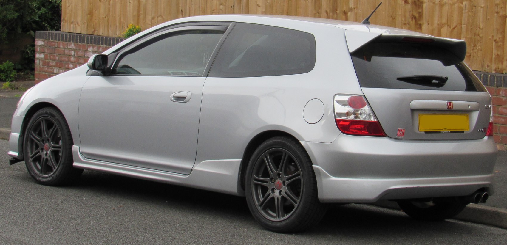 Rear side view showing black alloy wheels and sporty rear spoiler design.