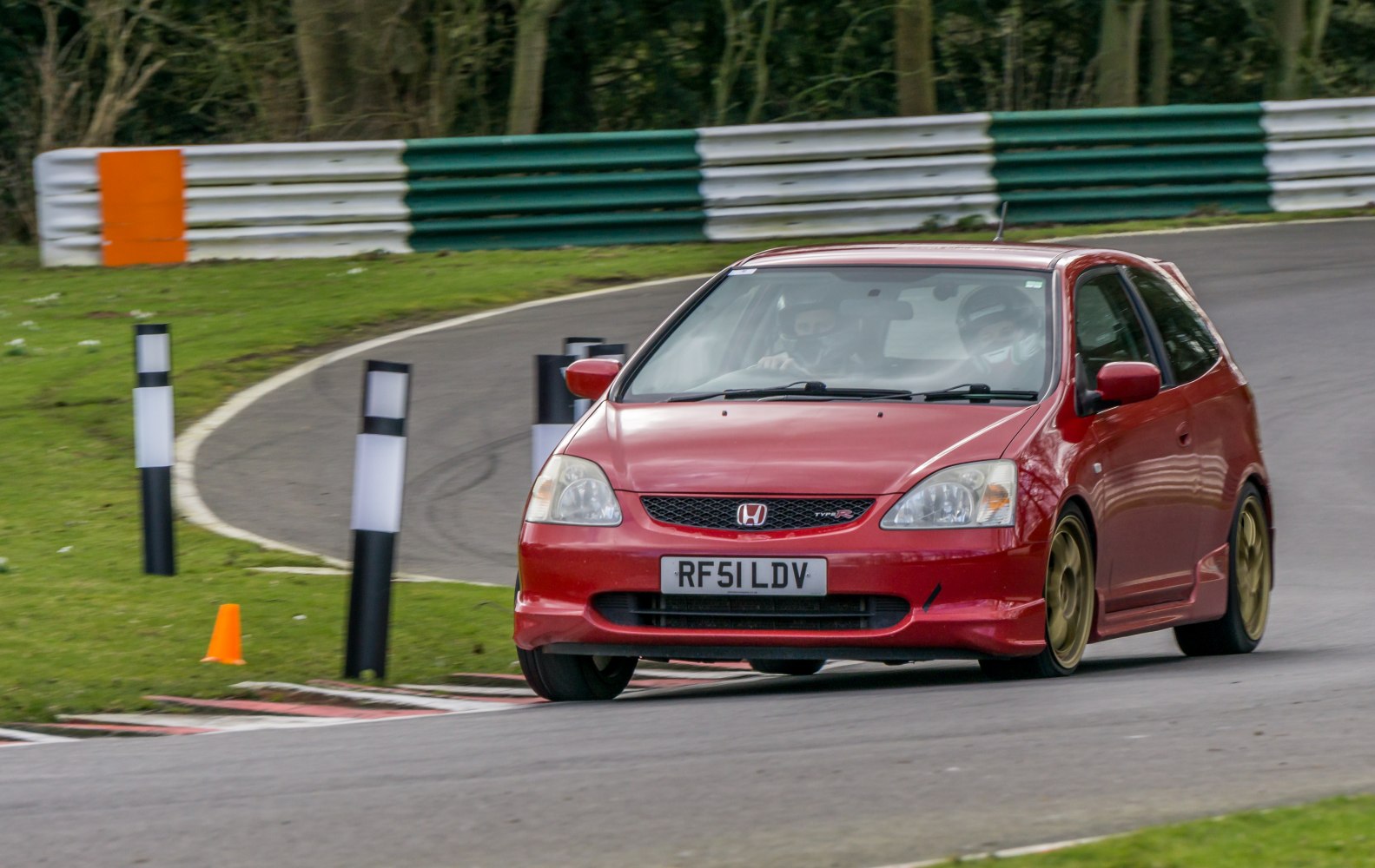 Red sporty hatchback on race track with gold alloy wheels