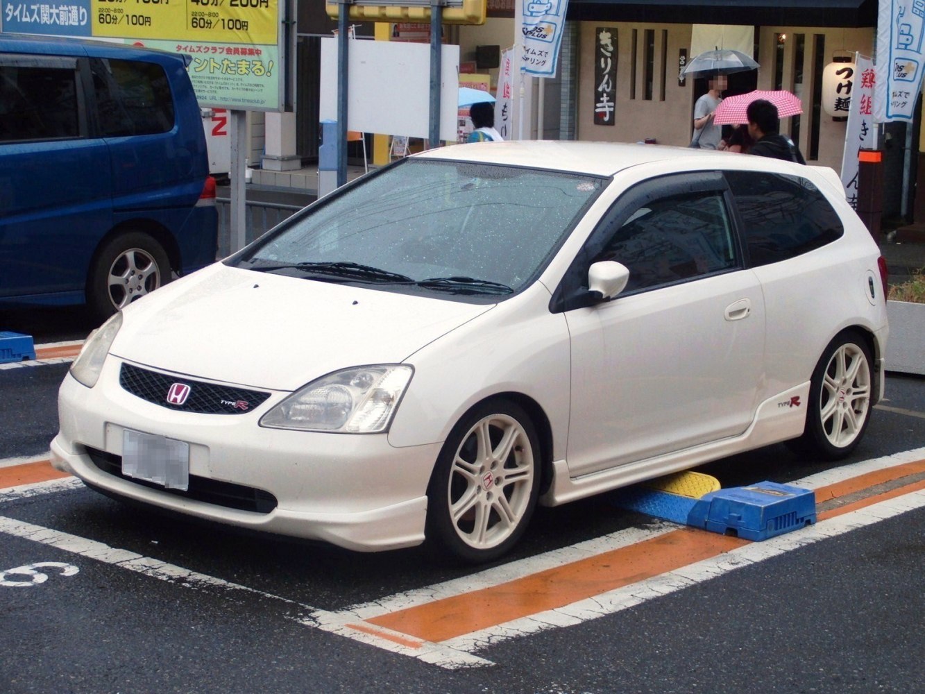 White compact hatchback with sporty alloy wheels and aerodynamic body kit