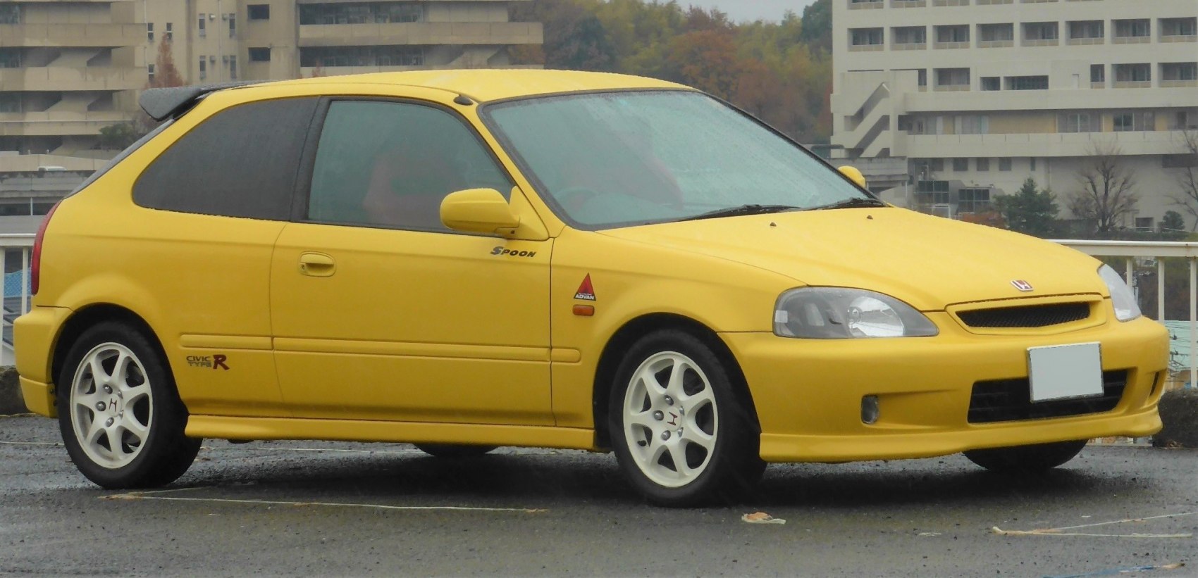Yellow hatchback with white alloy wheels and rear spoiler