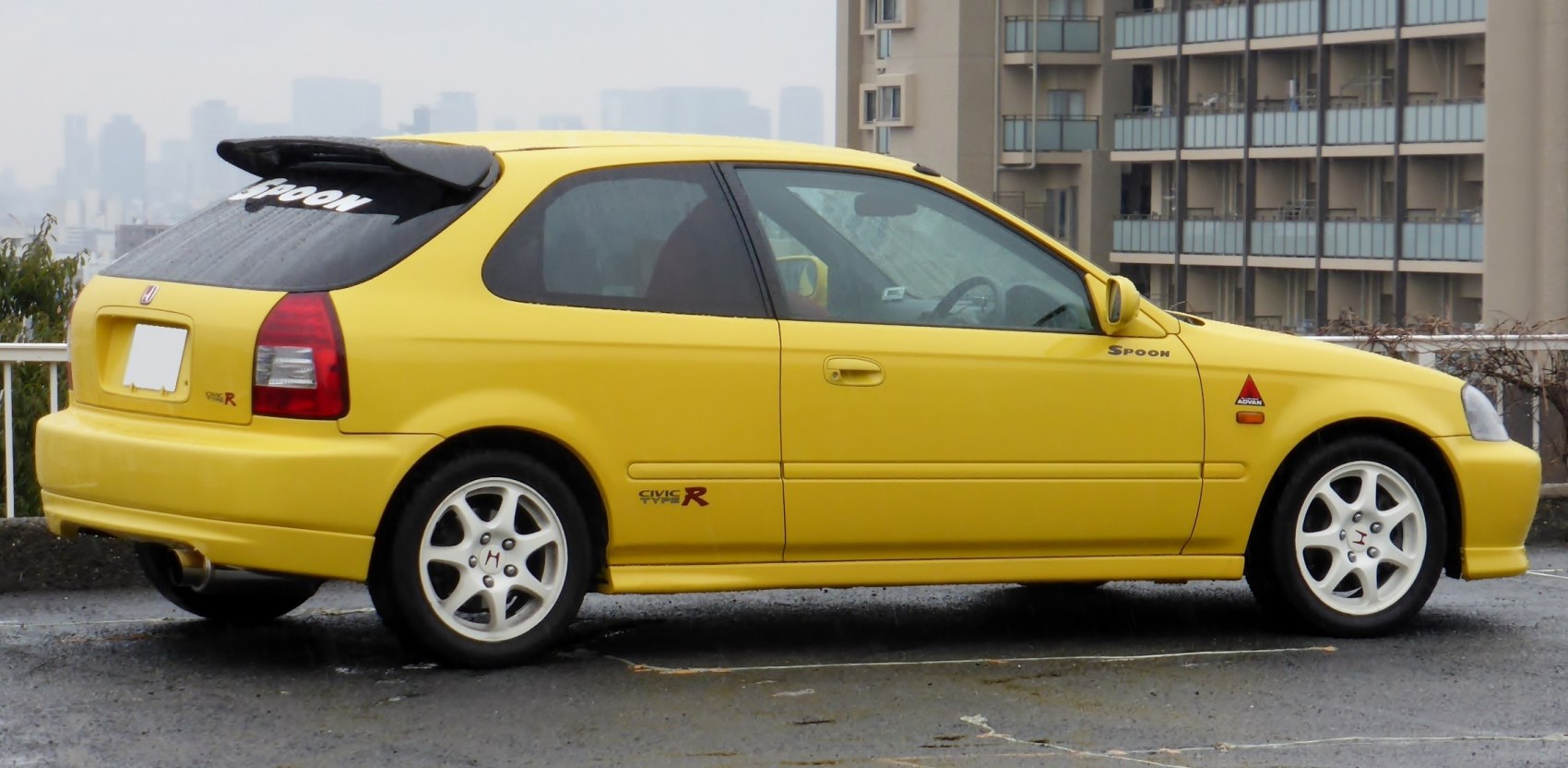 Yellow sporty hatchback with white wheels and decals