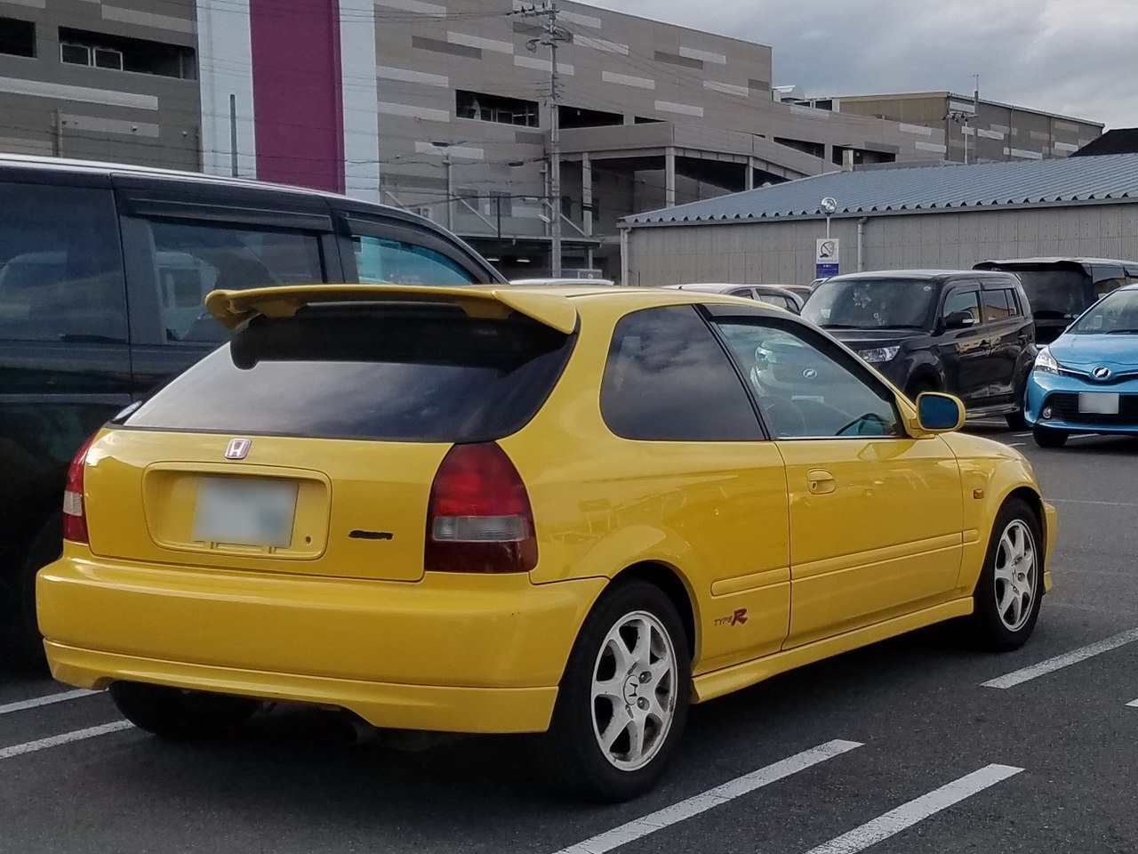 Yellow hatchback rear with spoiler and white multi-spoke wheels