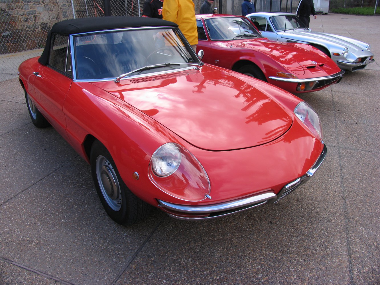 Vintage red convertible with black soft top, round headlamps, chrome bumper