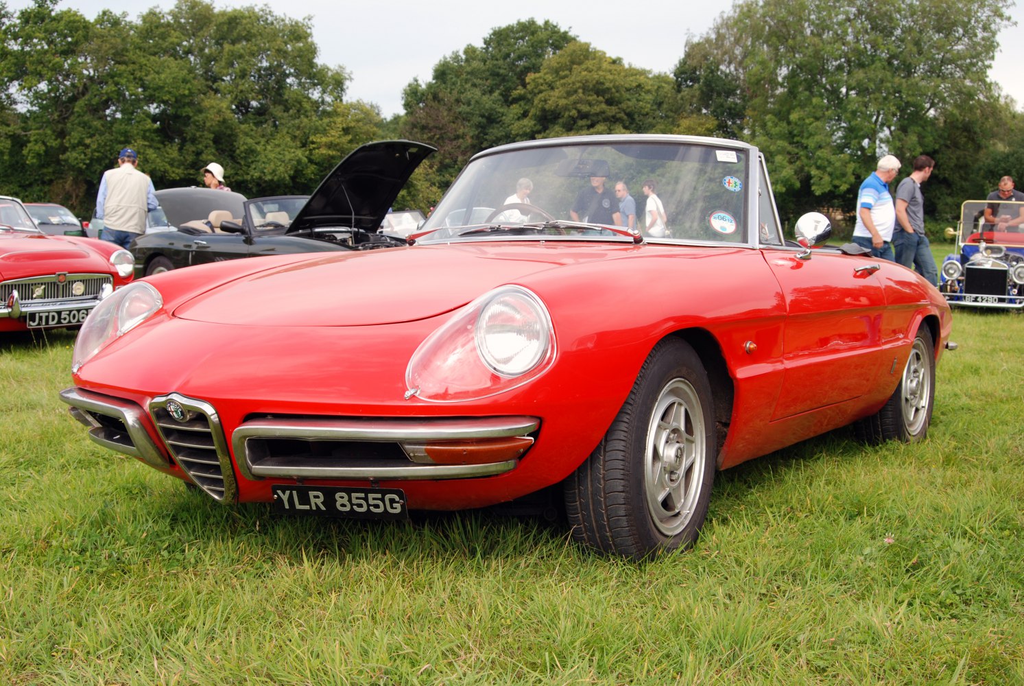 Red convertible sports car with rounded headlights and chrome grille.