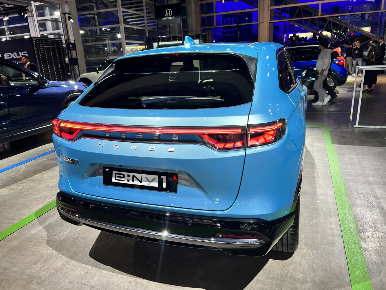Rear view of a blue electric SUV with full-width LED tail lights and modern styling.