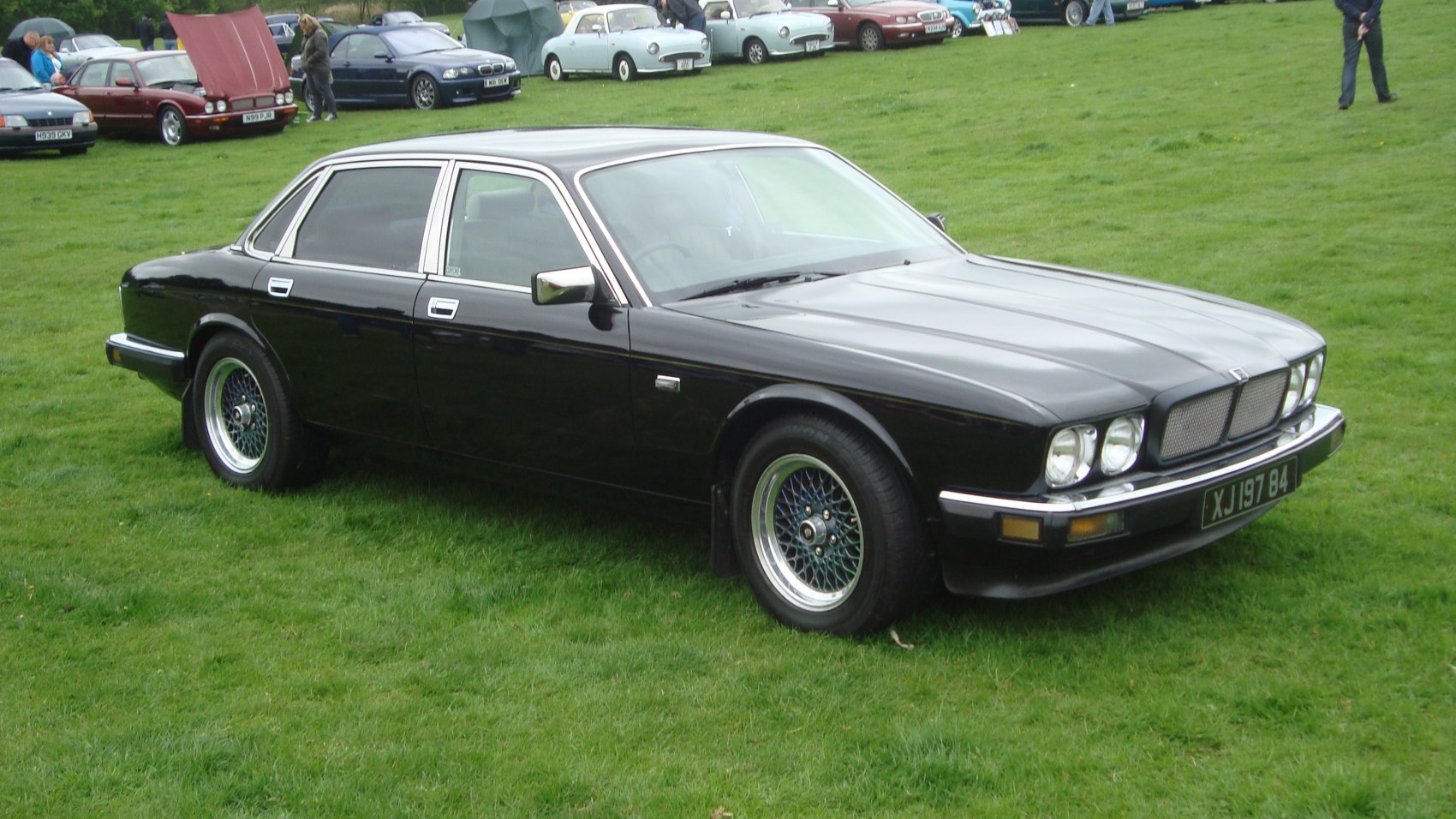 Black luxury sedan with wire mesh alloy wheels and chrome trim