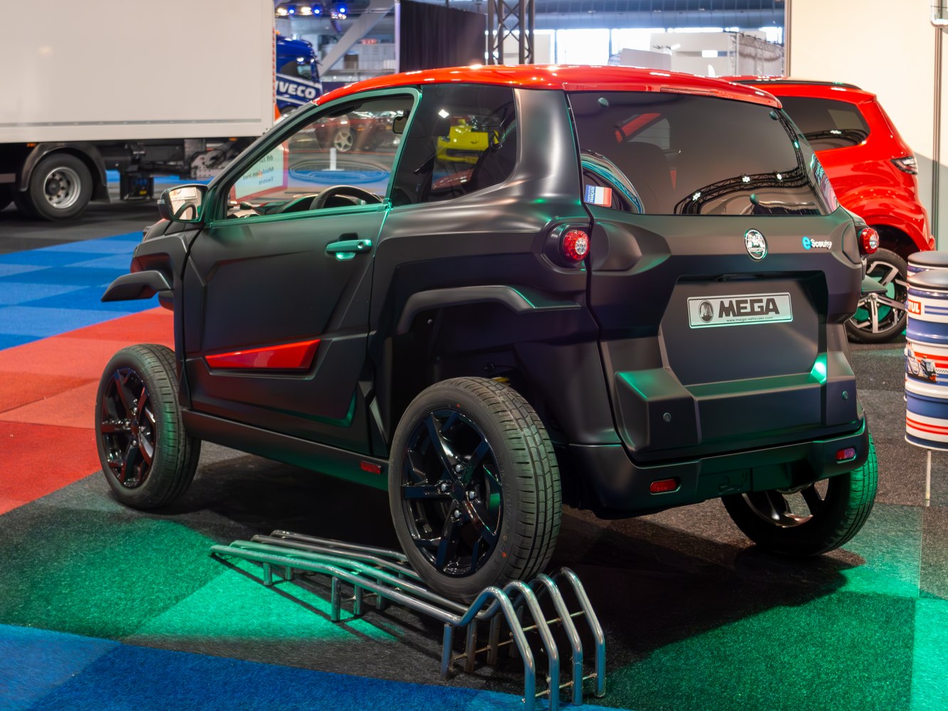 Rear view of an electric microcar with black alloy wheels on display indoors
