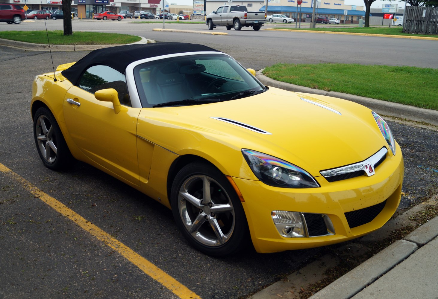 Yellow convertible roadster with black soft top and chrome wheels