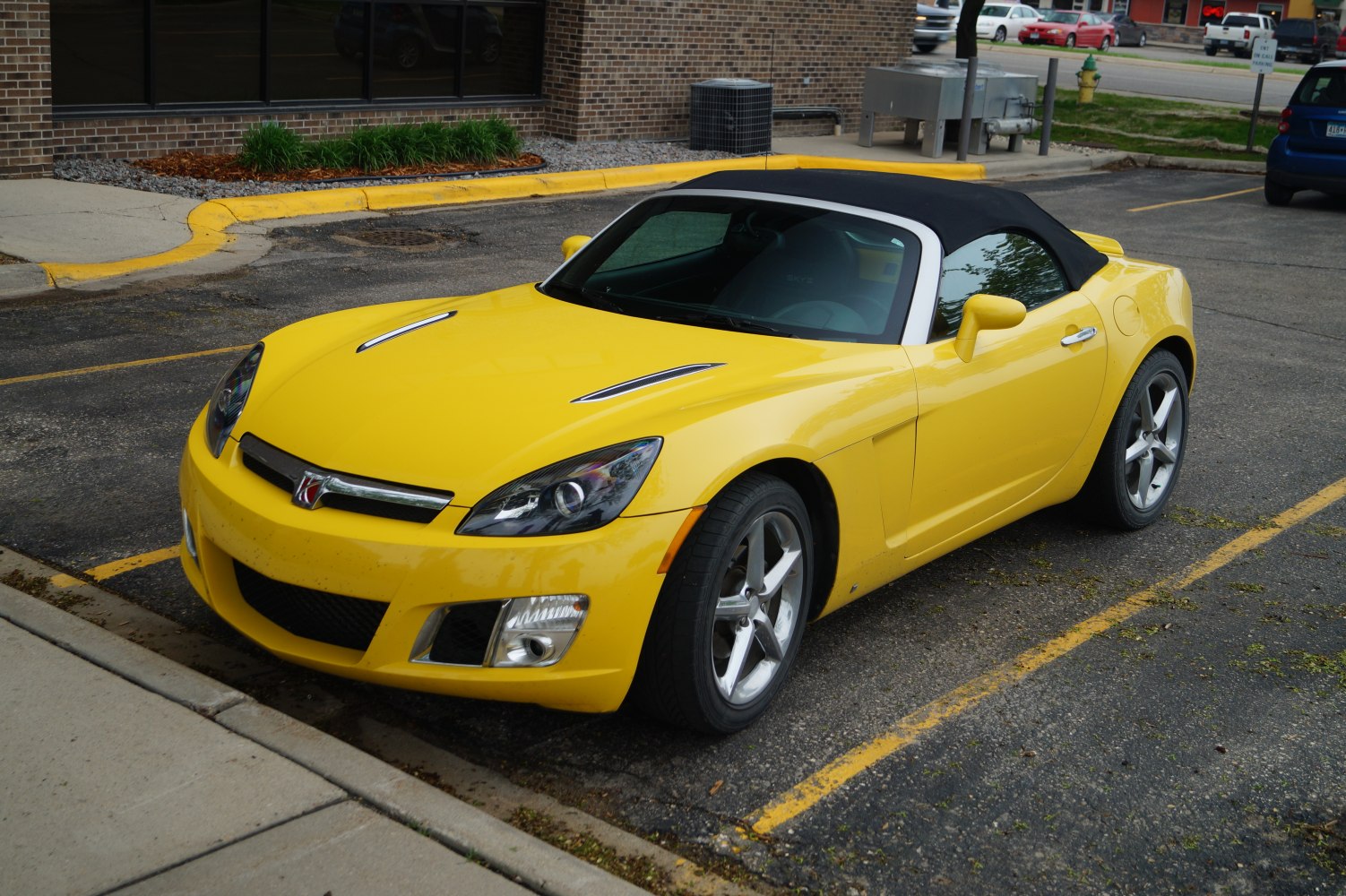 Yellow convertible roadster with black soft top and sporty aerodynamic design