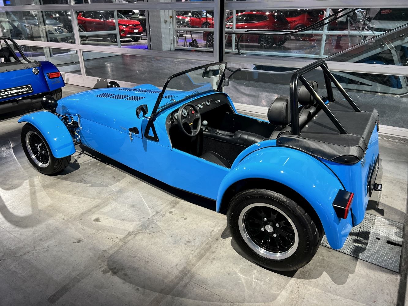 Open-top vintage roadster with black alloy wheels and roll bar