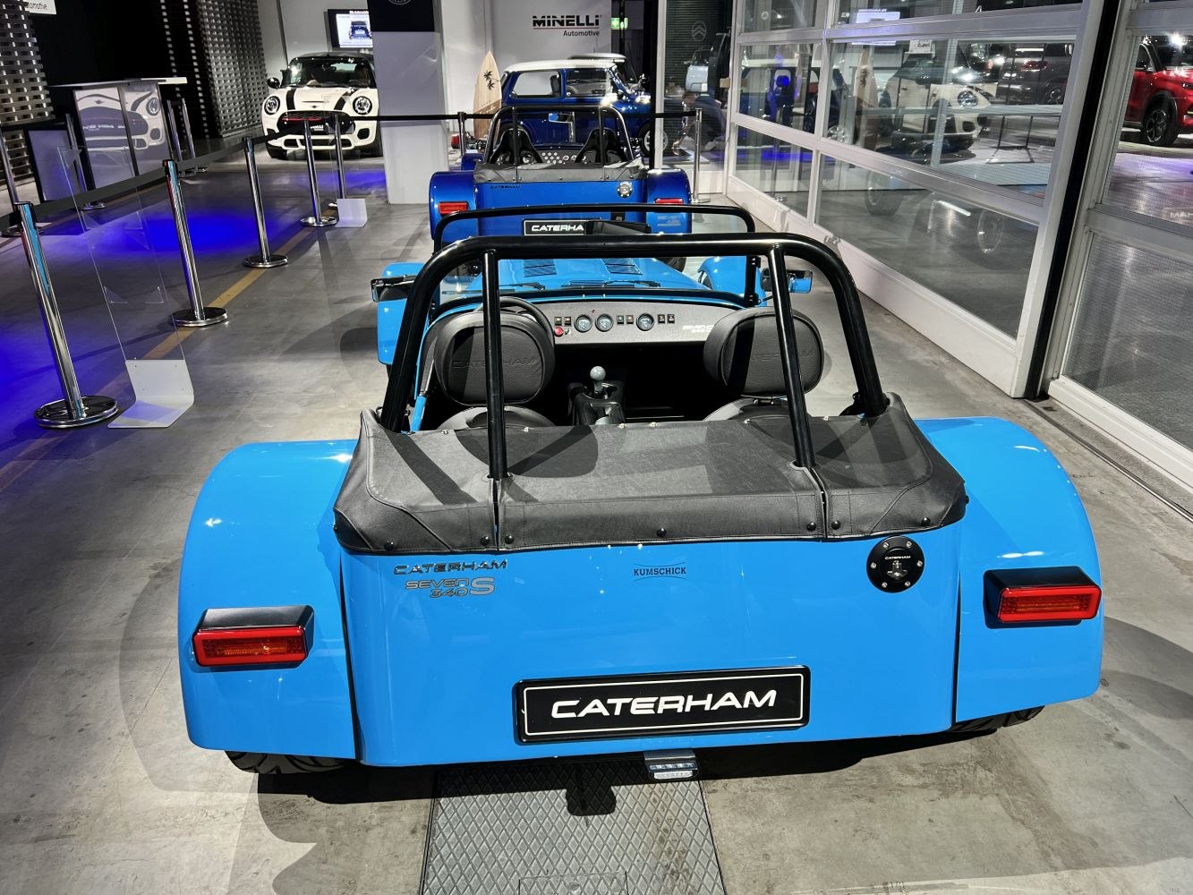 Rear view of blue open-top roadster with roll bars and dual headrests.