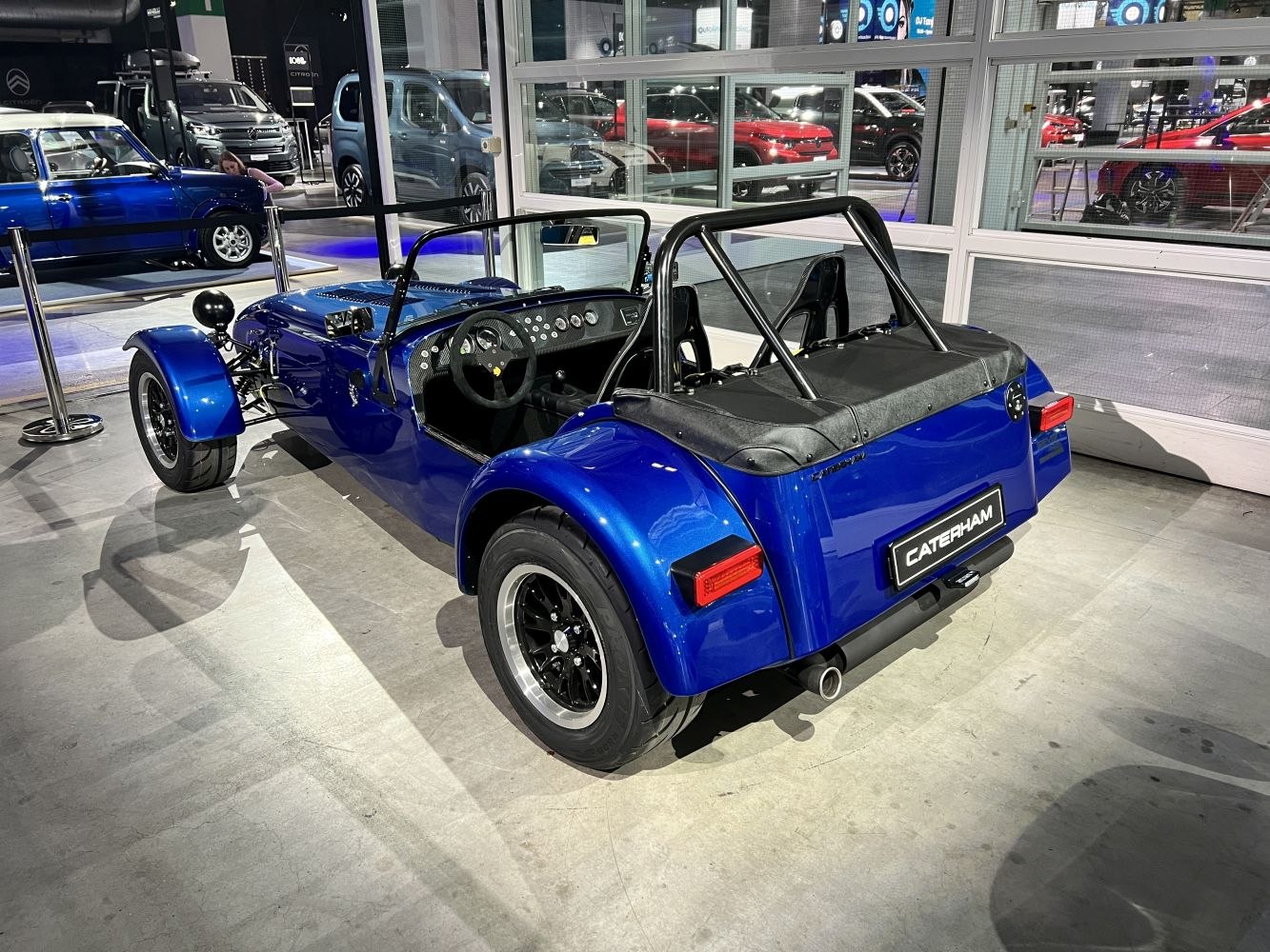 Blue open-top lightweight sports car with roll cage and rear exhaust