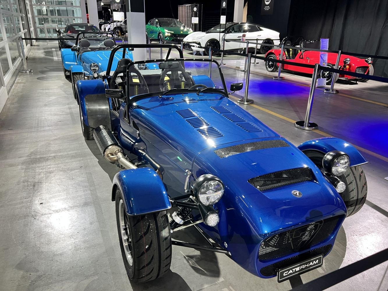 Blue lightweight open-wheel roadster with exposed suspension and hood vents