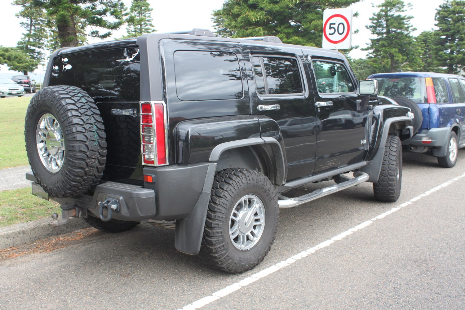 Side-rear view of black SUV with off-road tires and rear spare tire