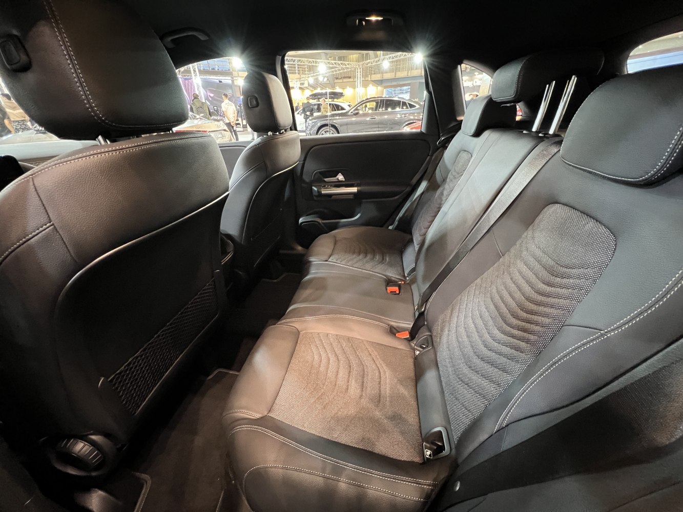 Spacious rear seat with leather and fabric upholstery, headrests, and seat belts.