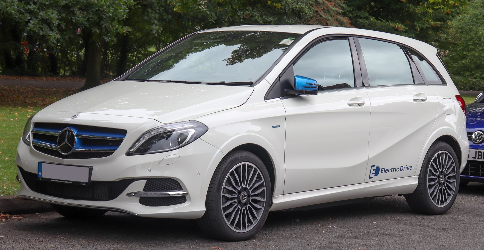 White electric compact hatchback with blue accents and alloy wheels front side view