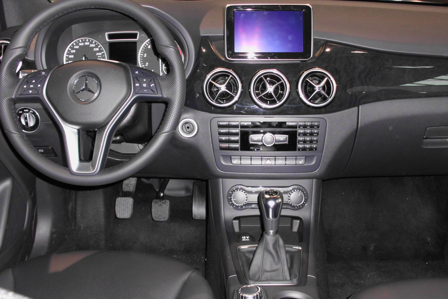 Dashboard with steering wheel, manual gear shift, and circular air vents
